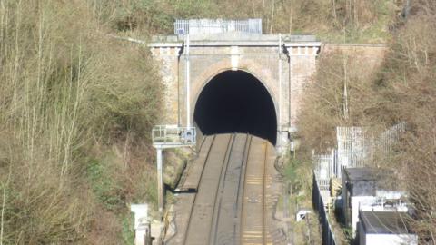 Merstham tunnel in Surrey. The image has been taken from a bird's eye view and shows two tracks into the tunnel, which has a big arch.