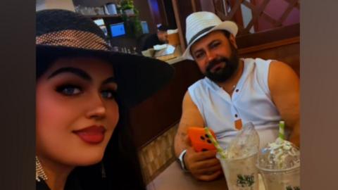 A man and a woman wearing hats sit in a coffee shop.