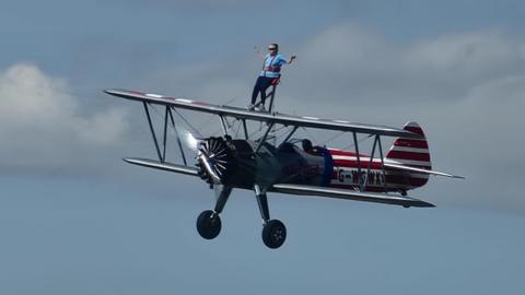Long distance shot of Mel Griffiths, with arms outstretched, during her wing walk