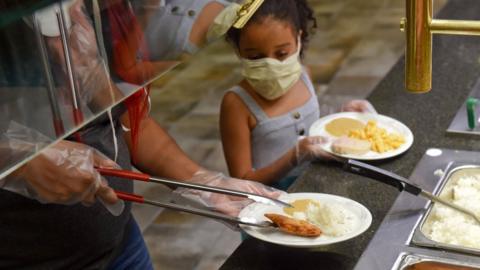 a little girl is served at a buffet