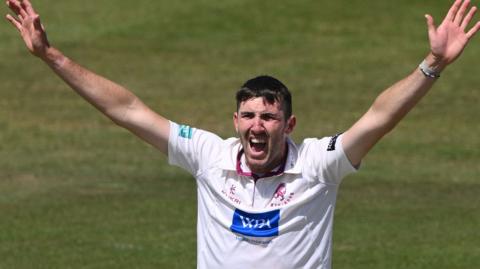 Craig Overton celebrates a wicket with his arms aloft