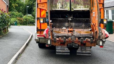 An orange bin lorry on a residential street