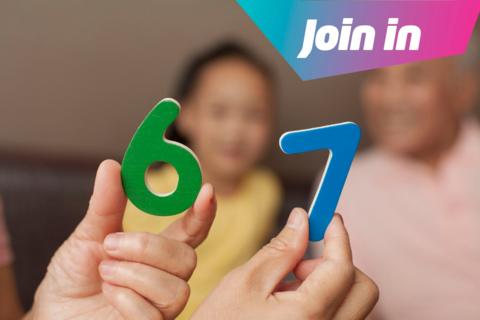 Person holding up wooden numbers '6' in green colour and '7' in blue colour to the camera.