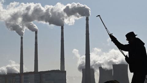 A worker uses a torch to cut steel pipes near the coal-powered Datang International Zhangjiakou Power Station in China