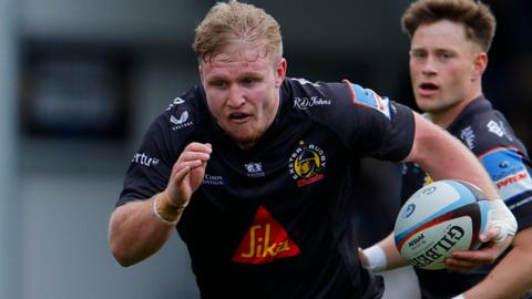 Max Norey wearing a black Exeter rugby shirt in action for the club.