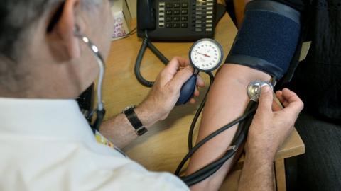 A doctor checking blood pressure on a patient.