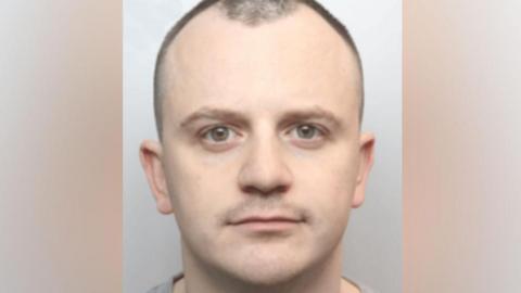 PC Dean Dempster with brown eyes and receding black hair looking impassively 