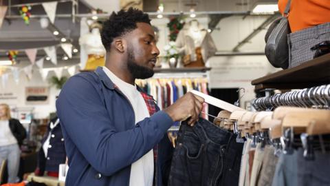Someone looking through clothes on a rack in a shop.