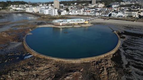 A general view of the lido. There is a large body of water with houses and buildings in the distance.
