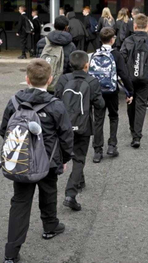 A line of children make their way into school
