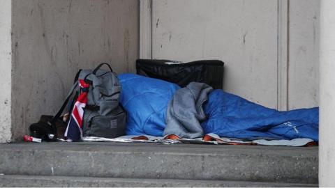 A backpack on the floor next to a blue sleeping bag in what appears to be a doorway