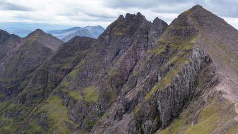 The mountain An Teallach looks like a jagged row of sharp teeth. The ridge has sheer, rocky cliffs.