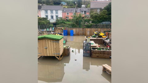 Buarth chwarae ysgol sydd dan ddŵr gwastraff.