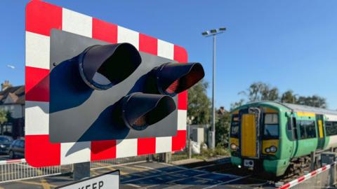 A railway level crossing with a green Southern train going across it.