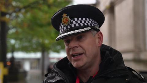 Assistant Chief Constable Chris Sykes, wearing his black Greater Manchester Police cap and a large black jacket