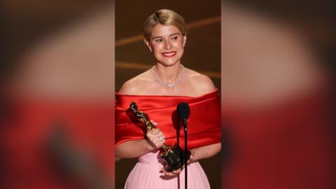 Jessie Buckley is seen holding an Oscars award.