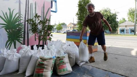 A man sets sandbags in front of his business as Tropical Storm Barry approaches land in New Orleans