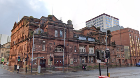 A large red brick theatre, sitting on a street corner