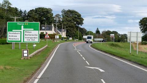 The A9 near Tomich showing a large green road sign with the directions for various locations including Thurso, Scotsburn and Barbaraville. 