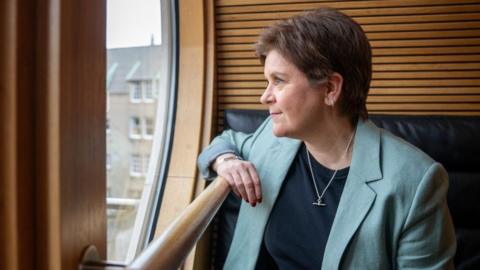 Nicola Sturgeon, who has short fair hair, looks out of a window in her office
