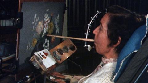 Elizabeth Twistington Higgins uses her mouth to hold a paintbrush and paint