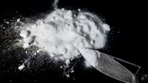 A shot of some white powder on a black surface with a blade or razor