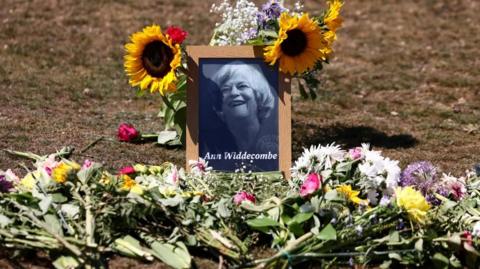 Tributes and flowers to Ann Widdecombe around a framed photograph of her