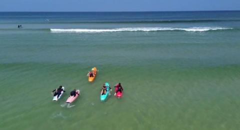 four paddle boards in yellow, multi coloured, pink, blue and red have set off in the waves at Hayle