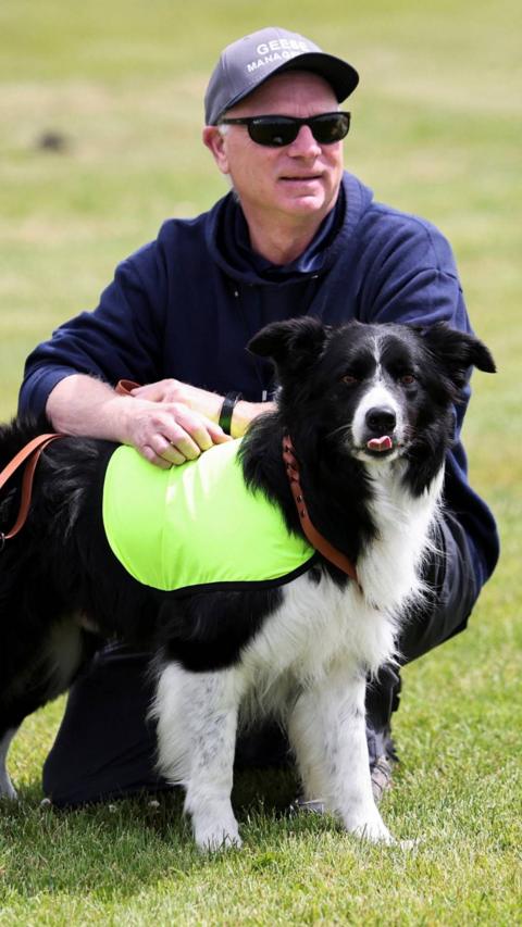 Gareth Williams, owner and operator of Border Control Bird Dogs, a specialised geese management company, holds Ben, one of two border collies hired to keep Canada geese off a FIFA World Cup training pitch, as they attend a practice session at the Centennial Park in Toronto, Canada.