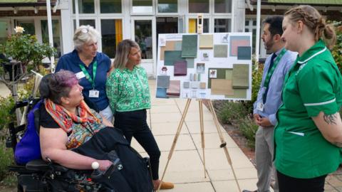 Hospice care staff and patients looking at a chart outside a hospice.