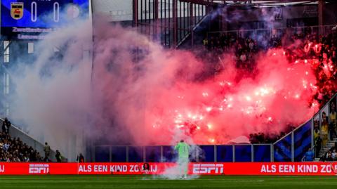 Feyenoord supporters set off fireworks and throw them onto the pitch near goalkeeper Tjark Ernst during their match at SC Cambuur