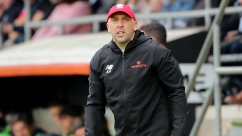 York City boss Adam Hinshelwood stands in his technical area at a match