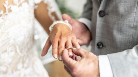 A man puts a ring on a bride's finger