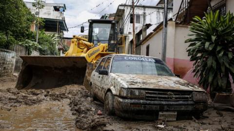 A car is buried in the mud after heavy rain hits Macarao parish in Caracas, Venezuela on June 25, 2021.