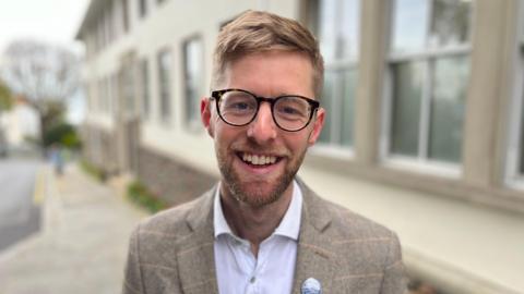 Deputy Andy Taylor smiling towards thje camera wearing a tweed suit and a badge.