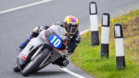 Paul Jordan on a silver and black machine with the number 10 in a blue plate on the front. His helmet is purple and yellow.