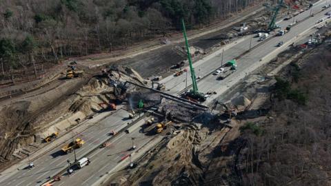 Workman on the section of the M25 between Junctions 10 and 11, in Surrey, that is closed in both directions while a bridge is demolished and a new gantry is installed