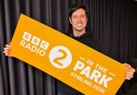 Radio 2 DJ Vernon Kay holding a sign promoting BBC Radio 2 in the Park Stirling 2026