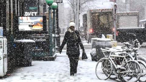 A woman walks through a snowy street in New York City on Tuesday morning