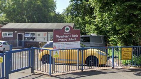 A school gate with a sign reading Woodlands Park Primary School 