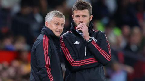 Ole Gunnar Solskjaer and Michael Carrick talking on the touchline during a game in 2021