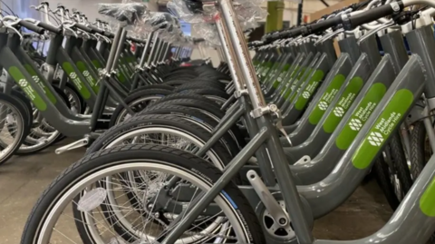 A row of green and grey West Midlands cycle hire bikes