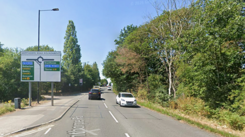 A road with a roundabout and road sign on the approach