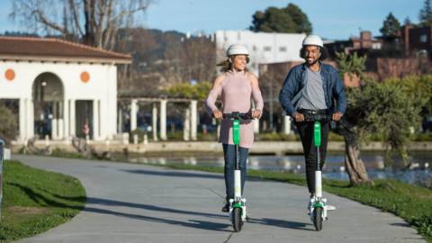 Two people riding Lime Scooters