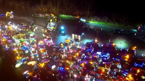 hundreds of tractors light up like christmas trees on a field