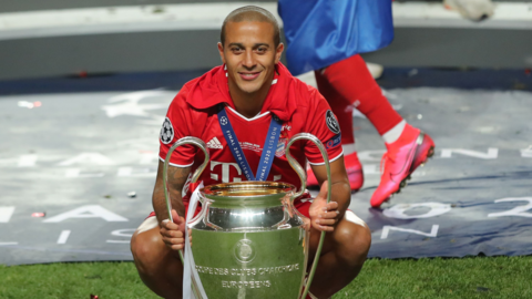 Thiago crouches down with the Champions League trophy