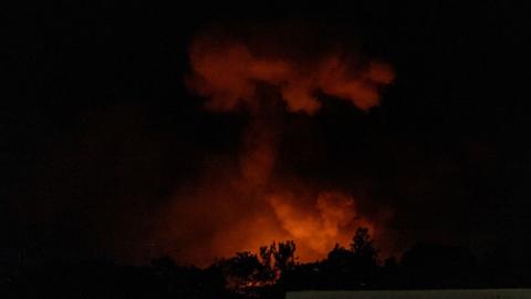 A plume of smoke rises in the dark