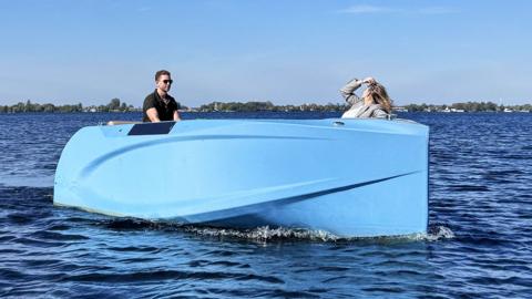 A man and a woman sat in a blue speedboat on open water