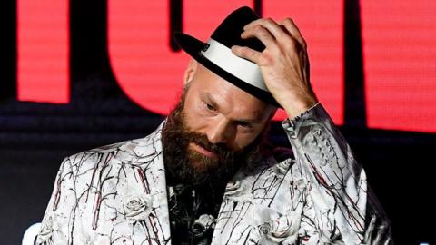 Tyson Fury in a white suit with black shirt and trilby hat