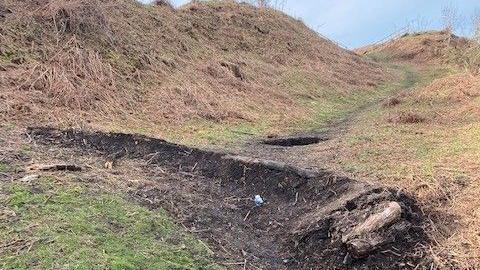 A hollow is carved out of the monument site where a bump has been created for bikes. There is pit visible in the background.